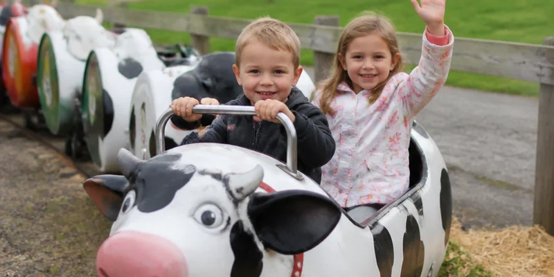 Children riding cow train with farm animals and families on spring day Sauvie Island Oregon